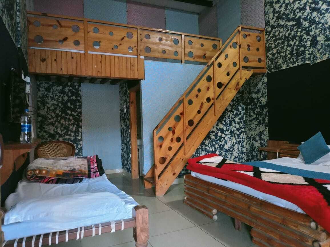 A room with bunk beds, a wooden staircase, and a small desk.