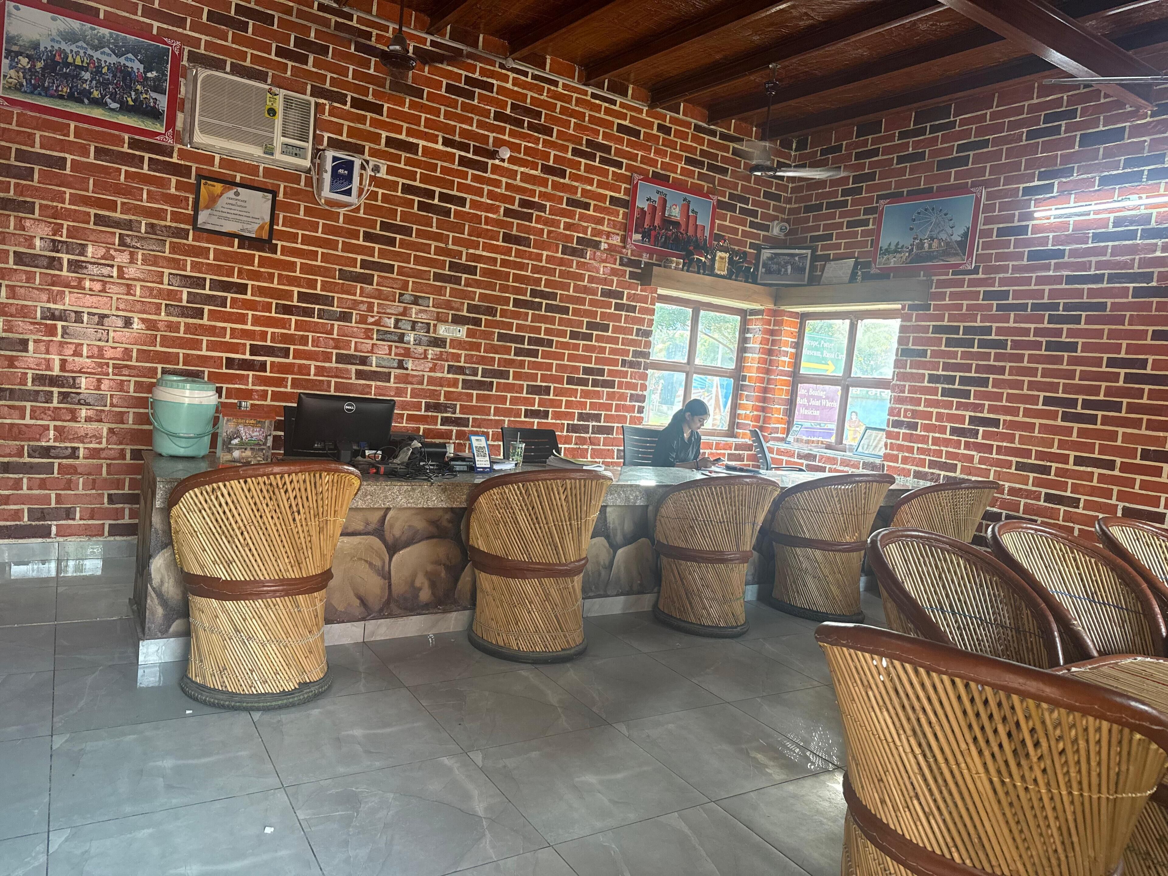 A reception area with a brick wall, a computer, and wicker chairs.