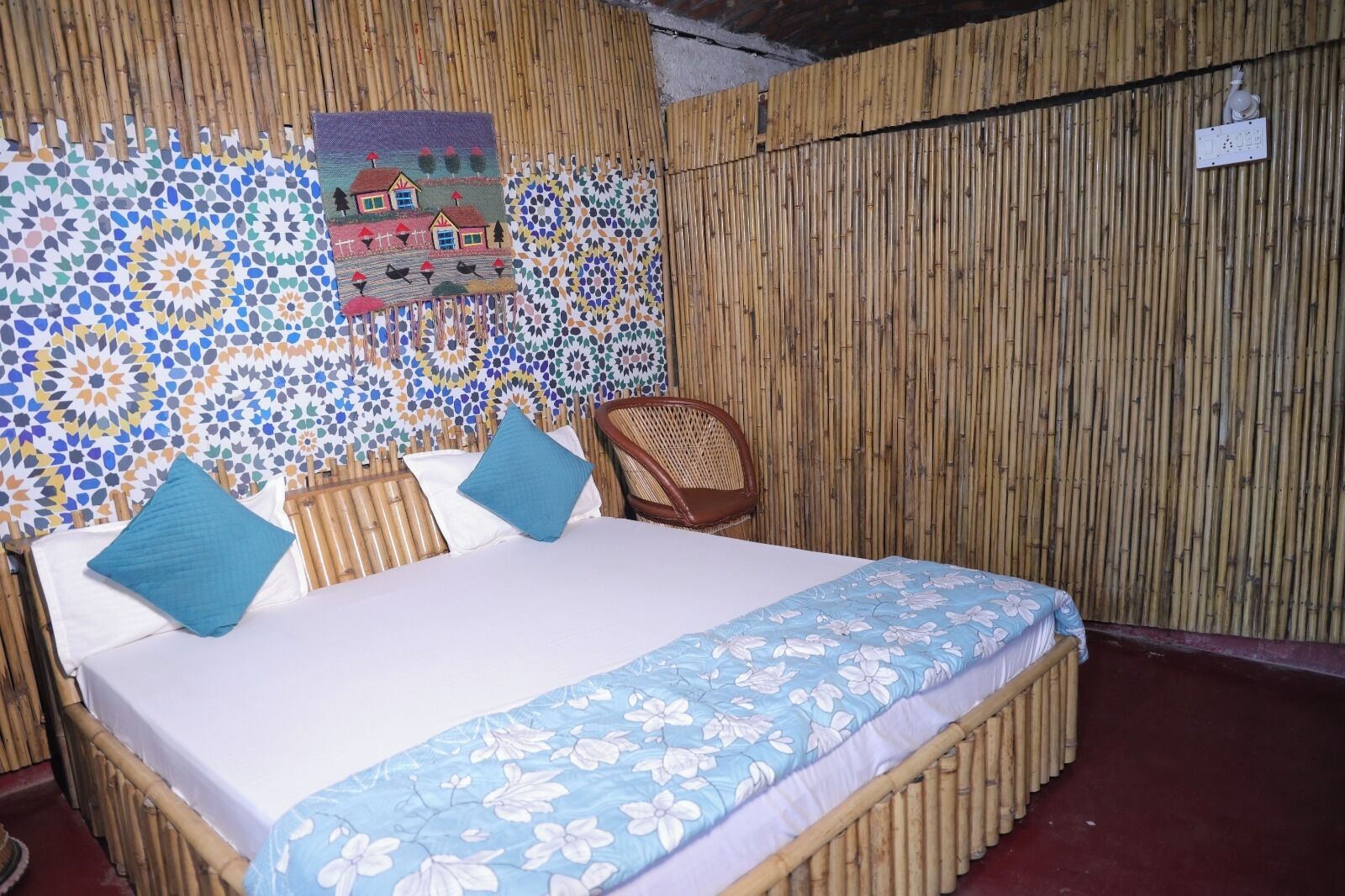 Una habitación con una cama, dos almohadas, una silla y una pared con diseño de mosaico.
