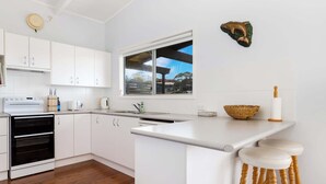 Eine moderne Küche mit weißen Schränken, einem Backofen, einer Spüle und einem Fenster mit Blick nach draußen.