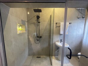 Bathroom features a glass-enclosed shower area with handheld and rain showerheads, a pedestal sink, and a towel rack.