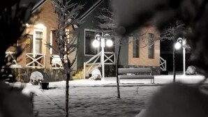 A snow-covered outdoor area with a building, street lamps, and a bench. - Tulpan Hotel (Sheki)