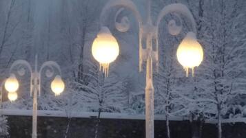 A snow-covered park with benches and decorative street lamps.