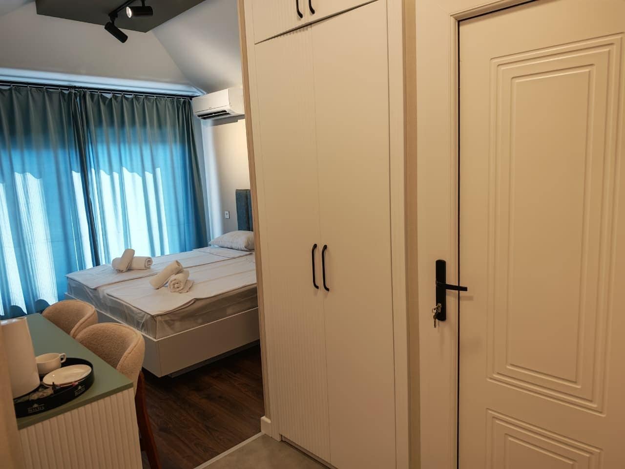 Ein Hotelzimmer mit einem Bett, einem Schreibtisch mit Stuhl, einem Kleiderschrank und einer Tür.