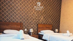 A hotel room with two beds, wooden headboards, and a patterned wall. - Tulpan Hotel (Sheki)