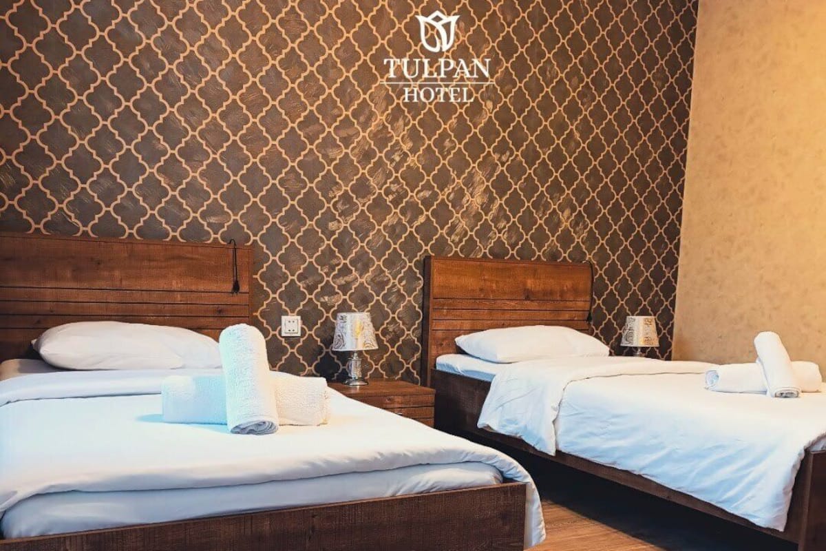 Une chambre d’hôtel avec deux lits, des têtes de lit en bois et un mur décoré d’un motif.