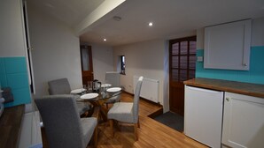 A compact kitchen with a dining area, a built-in refrigerator, and a small cabinet. - Cosy bungalow with amazing views  (Filey)