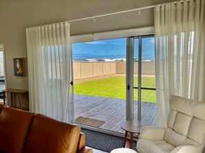 Een kamer met een schuifglazen deur die uitkomt op een terras met uitzicht op de oceaan.