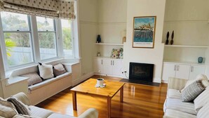 A living room with a sofa, a coffee table, a TV, and a painting on the wall. - Saltwater Bungalow - WiFi (Robe)