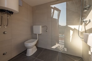 A modern bathroom with a toilet, a shower, and a glass door leading to an outdoor area. - Villa Ika (Benkovac)