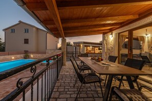 An outdoor patio with a pool, dining table, and chairs. - Villa Ika (Benkovac)