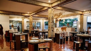 Un restaurante con piso de mármol pulido, mesas y sillas de madera, e iluminación decorativa.