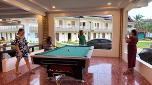 A pool area with a pool table, a car, and a view of a building with balconies. - On Board Lifestyle Panglao Resort (Panglao)