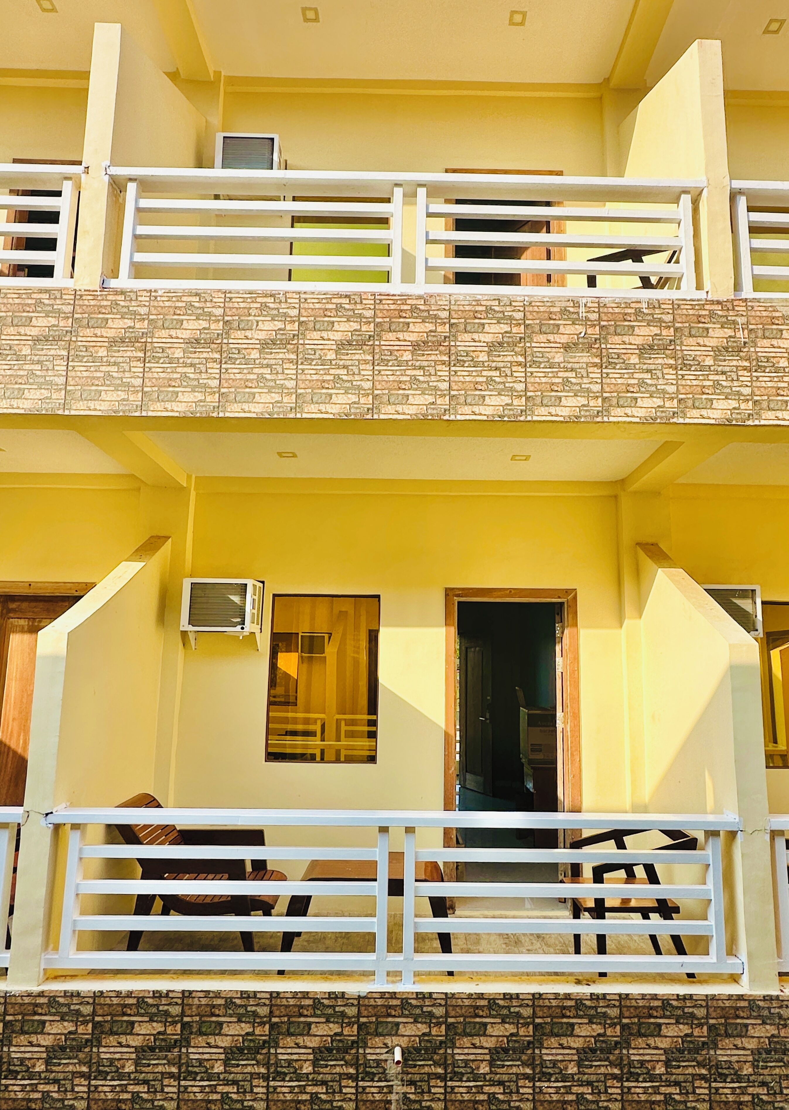 A two-story building with a balcony, a door, and an air conditioning unit.