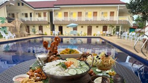 Un bufé junto a la piscina con camarones, arroz y diferentes acompañamientos.