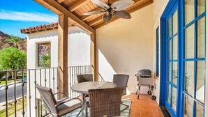 Une terrasse couverte avec une table et des chaises, un ventilateur de plafond et un barbecue.