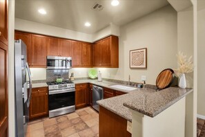 A kitchen with wooden cabinets, stainless steel appliances, and a granite countertop.