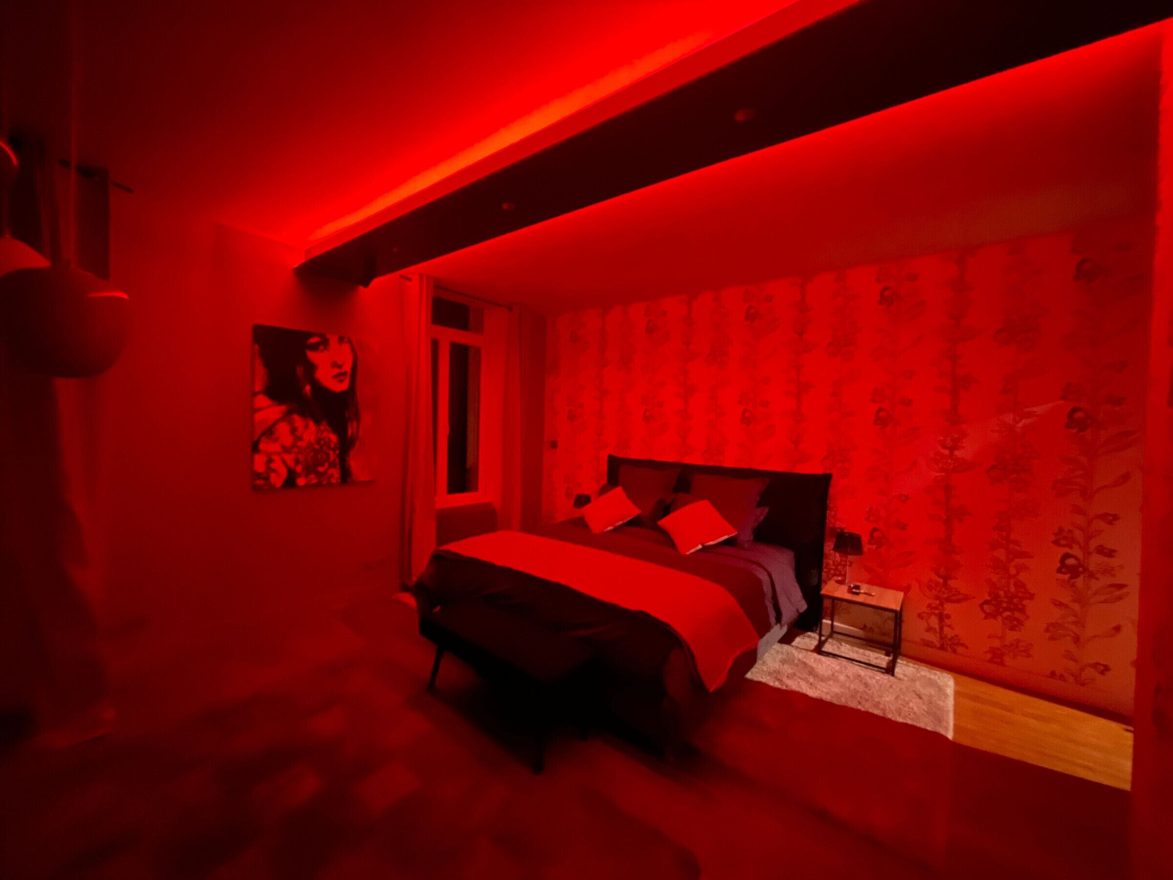 Quarto com cama, mesa de cabeceira e prateleira na parede.
