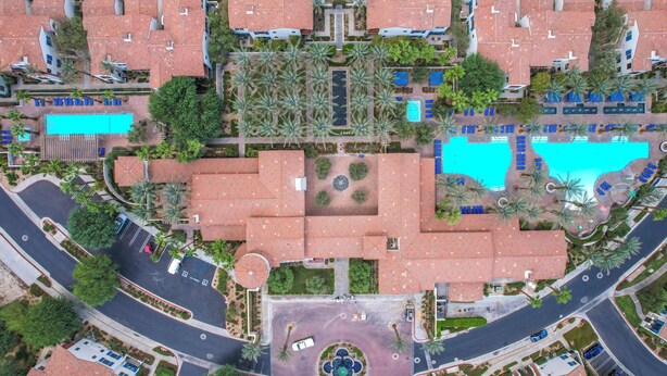 An aerial view of a resort with multiple buildings, swimming pools, and a central circular plaza. - The Desert Loft A | 1BR Legacy Villa (La Quinta)