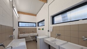 Baño público con dos lavamanos, una ventana y sistema de ventilación.