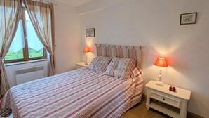 A bedroom with a bed, two bedside lamps, a nightstand, a window with curtains, and a wall-mounted picture. - Restored farmhouse near Loire Castles with Wi-Fi and secure parking (Sembleçay)