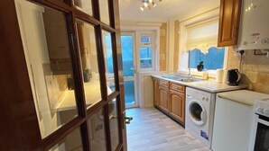 A kitchen with wooden cabinets, a washing machine, and a stove.