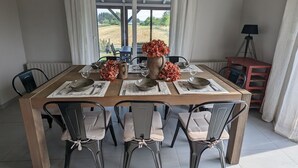 A dining table set with placemats, bowls, and a vase of flowers, surrounded by chairs. - Spacious house with spa, pets allowed, near Épinal (Dounoux)