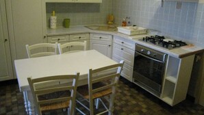A compact kitchen with white cabinets, a gas stove, an oven, and a dining table with chairs. - Cozy studio in Nancy, near center, wifi included (Nancy)