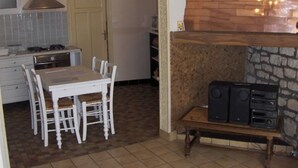 A compact kitchen with a dining table, chairs, a stove, and a built-in fireplace with a radio. - Cozy studio in Nancy, near center, wifi included (Nancy)