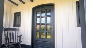 A black door with six glass panels, a small window above it, and a chair to the left. - Spacious lodge, modern comfort, peaceful garden (Saulcy-sur-Meurthe)