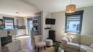 A modern living room with a sofa, armchairs, a coffee table, and a TV. - Spacious lodge, modern comfort, peaceful garden (Saulcy-sur-Meurthe)