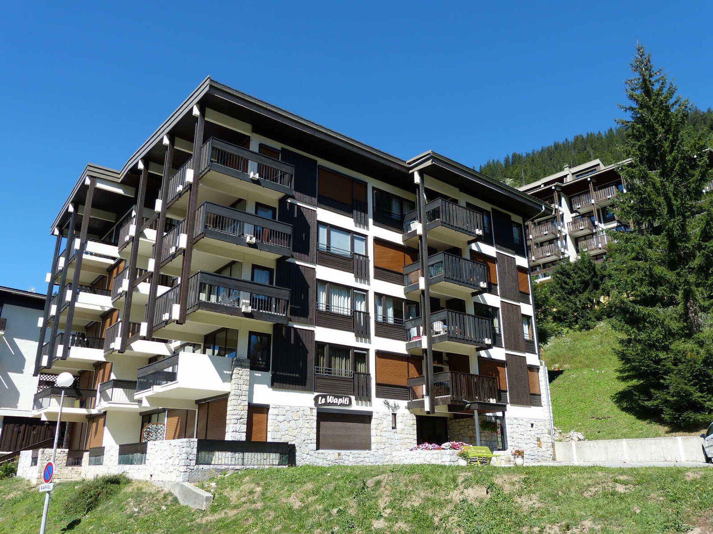 Um hotel de vários andares com varandas, fachada de pedra e uma placa com a inscrição 'Le Wapiti'.
