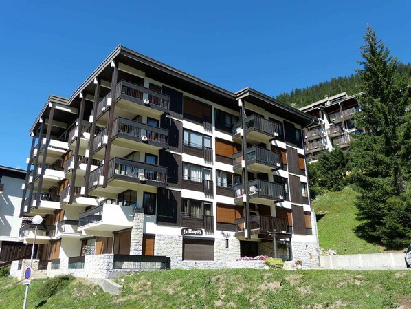 A multi-story hotel with balconies, stone facade, and a sign reading 'Le Wapiti'.