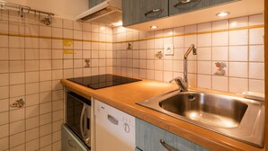 A kitchen with a dishwasher, a sink, and cabinets. - 3* Apartment near slopes and shops, Wi-Fi (La Clusaz)