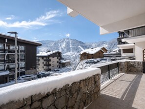 A snow-covered mountain town with buildings, a stone wall, and a clear sky.