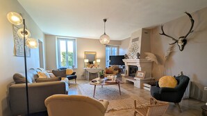 Una sala de estar con sofá, sillones, una mesa de centro, chimenea y televisor.