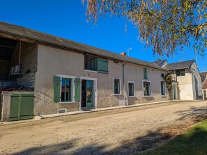 A two-story building with a dirt ground, green shutters, and a visible door.