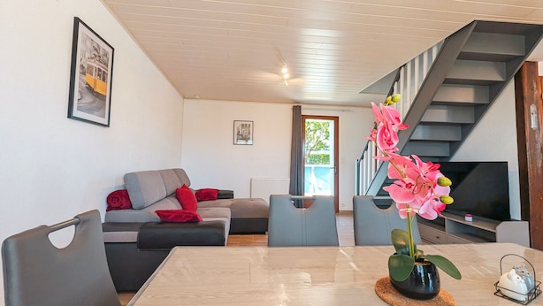 A modern living room with a sofa, a dining table, a staircase, and a TV. - Family cottage with shared pool, terrace, and WiFi (Ségry)