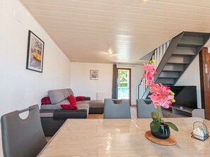 Un salon moderne avec un canapé, une table à manger, un escalier et un téléviseur.