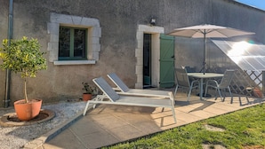 A patio with a table and chairs, a potted plant, and a small window. - Family cottage with shared pool, terrace, and WiFi (Ségry)