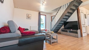A living room with a sofa, a small table, a TV, and a staircase. - Family cottage with shared pool, terrace, and WiFi (Ségry)