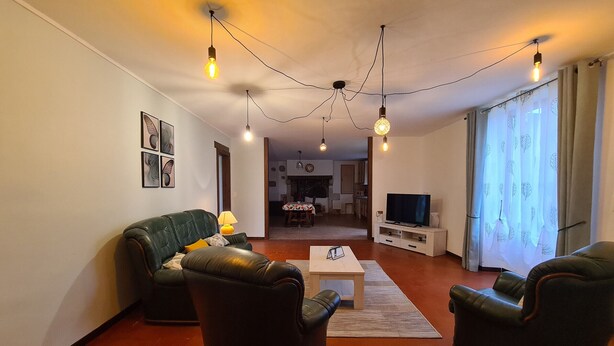 A living room with a sofa, a coffee table, and a TV. There are string lights on the ceiling.