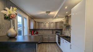 Une cuisine moderne dotée d’un îlot central, d’appareils électroménagers en acier inoxydable et de meubles de rangement en bois.