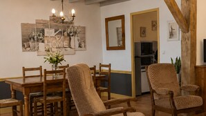 A dining area with wooden furniture, a chandelier, and a kitchen in the background. - Medieval house in Berry with private courtyard and all-inclusive (Saint-Benoît-du-Sault)