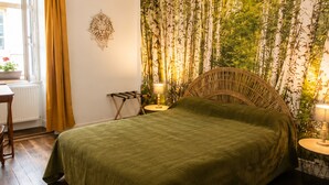 A bedroom with a bed, a nightstand, a lamp, a window with curtains, and a wall tapestry. - Medieval house in Berry with private courtyard and all-inclusive (Saint-Benoît-du-Sault)