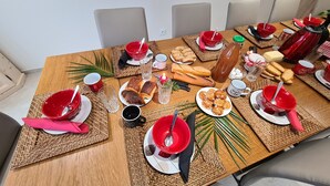 Ein Esstisch ist gedeckt mit roten und weißen Tellern, Schüsseln und verschiedenen Speisen wie Gebäck und Brot.