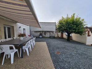 A patio area with a table and chairs, a barbecue grill, and a potted plant. - Family cottage near Beauval Zoo with private courtyard (Lye)