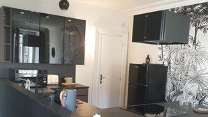 A modern kitchen with a black countertop, a built-in oven, a microwave, and a refrigerator.