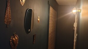 A room with a dark wall adorned with various decorative items, including a mirror, a heart-shaped ornament, and a wall-mounted light fixture.