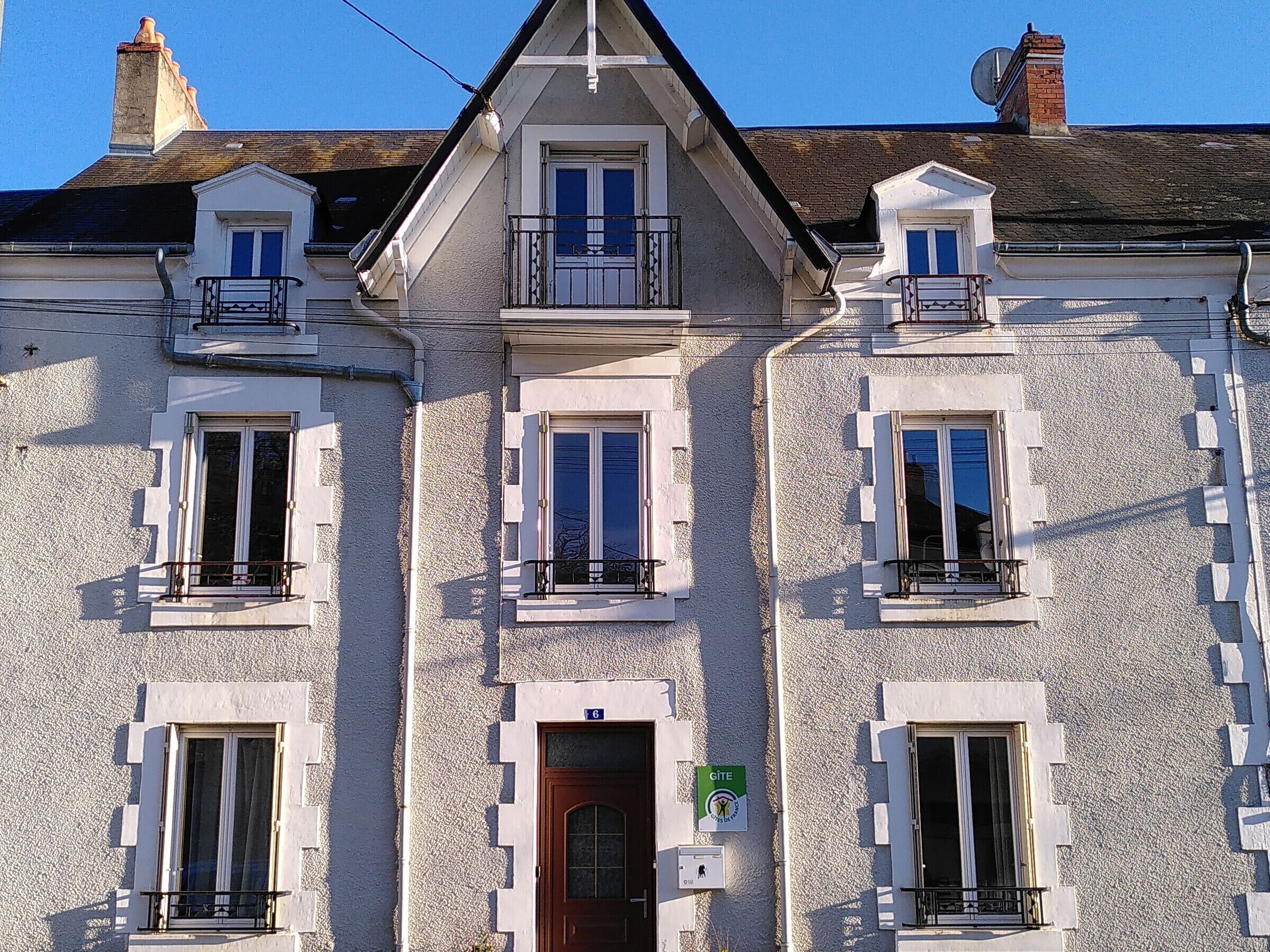 Ein Gebäude mit drei Fenstern, einer Tür und einem kleinen Balkon mit Geländer.